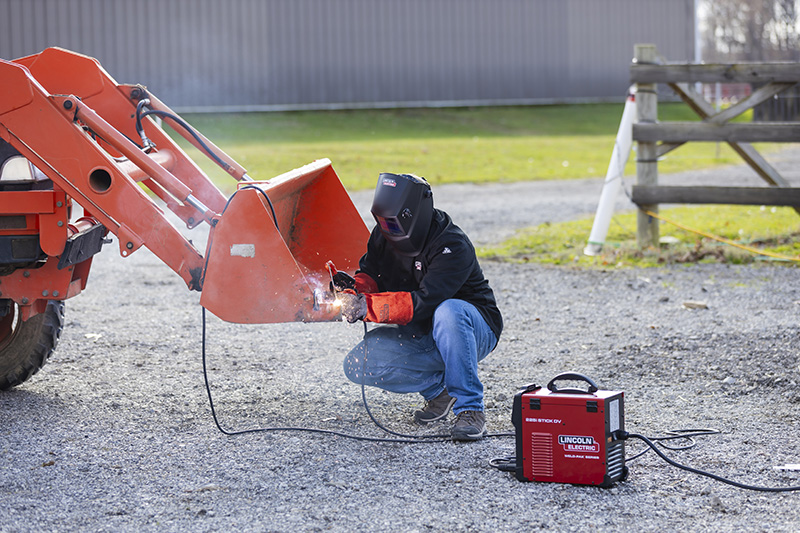 Worker using the 225i DV STICK WELDER on an excavator part